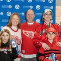 A family of five standing together by the Alumni Relations backdrop.